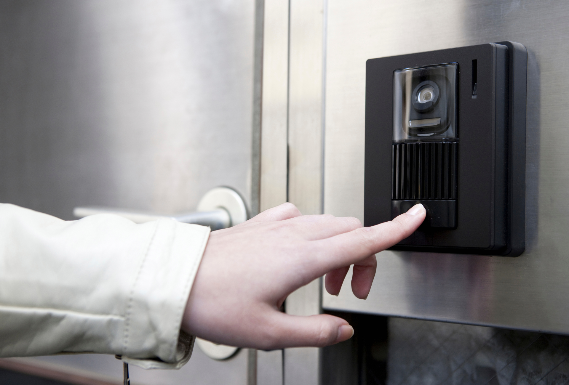 A person is pressing a button on a doorbell.